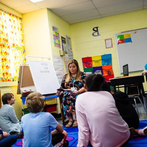 Teacher reading a book with young students 